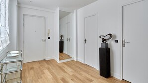 A modern hallway with white doors, a glass-topped table with bowls, and a black sculpture. - Luxurious Apartment Louvre Museum-palais Royal (Paris)