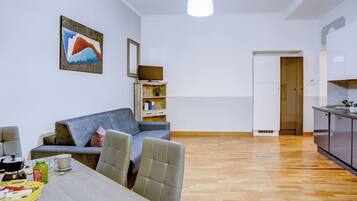 En moderne stue med en grå sofa, et spisebord med stole, et sofabord og et billede på væggen.