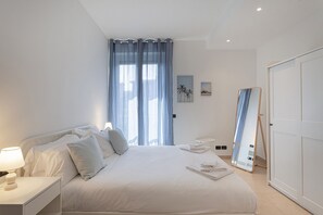 Quarto com uma cama, mesa de cabeceira e espelho na parede.