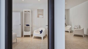 Une salle de bain moderne avec une baignoire blanche, une chaise blanche et une armoire blanche.