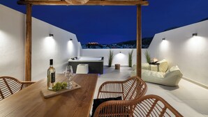 An outdoor patio with a wooden table, wicker chairs, a sofa, and a pool table.