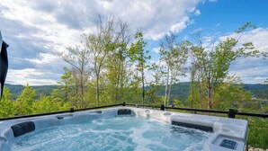 A hot tub with a view of a mountainous landscape and trees.