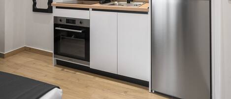 Une cuisine moderne avec des armoires blanches, un réfrigérateur en acier inoxydable, un four encastré et un plan de travail en bois.