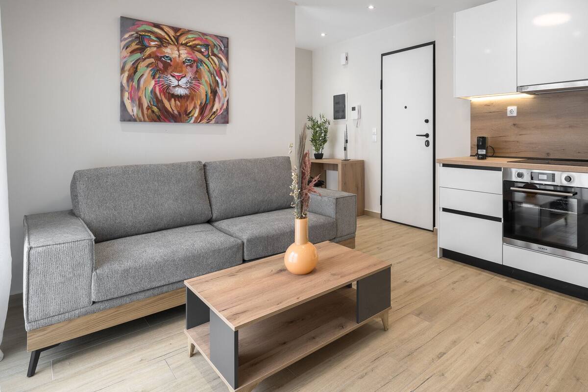 A modern living room with a grey sofa, a wooden coffee table, and a vibrant abstract painting on the wall.