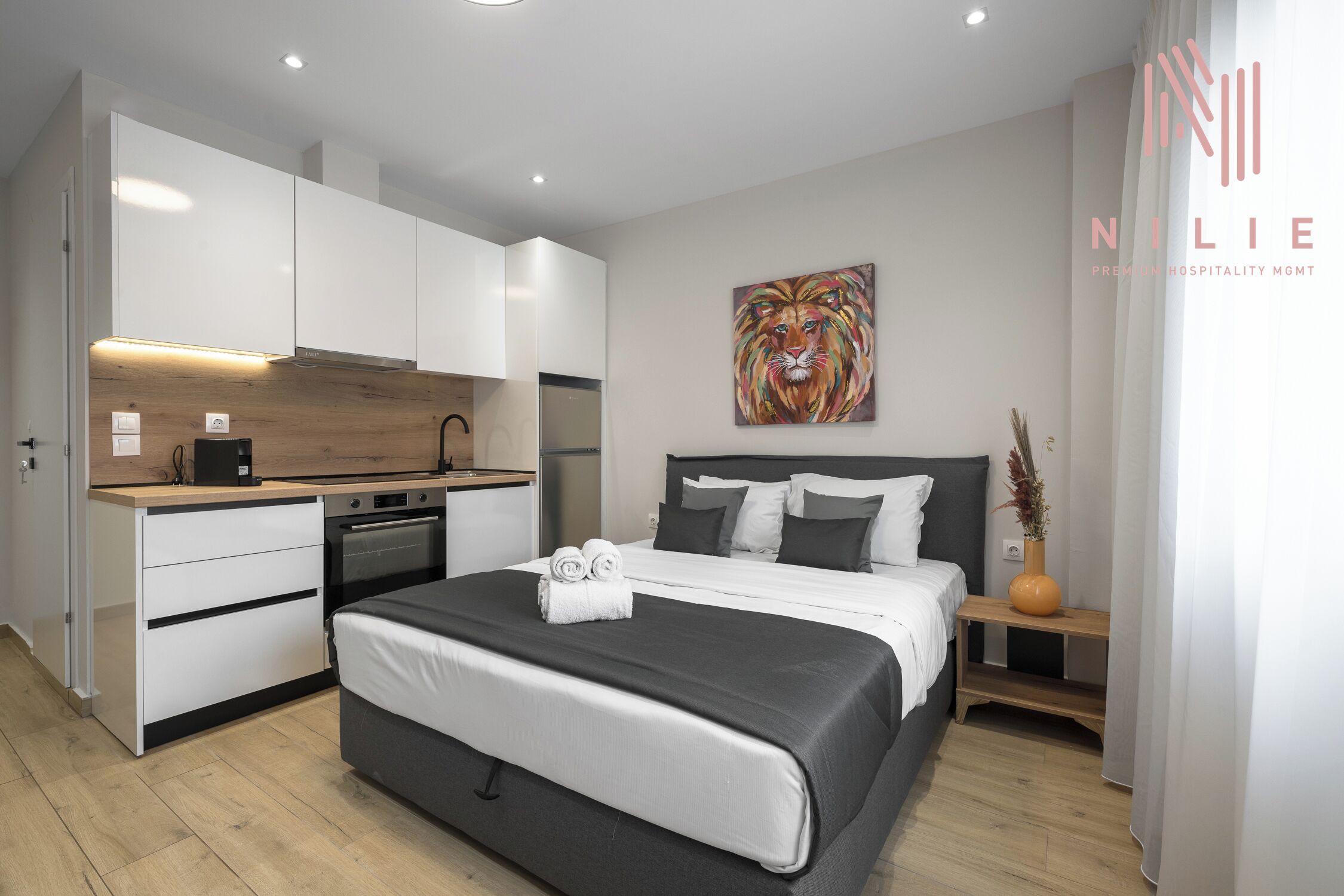 Una habitación de hotel moderna con una cama, una pequeña kitchenette y un cuadro en la pared.