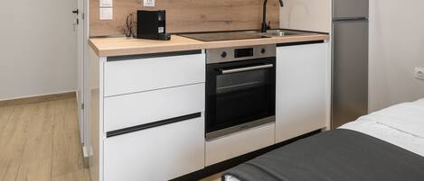 A compact kitchen with a built-in oven, a coffee machine, and a refrigerator.