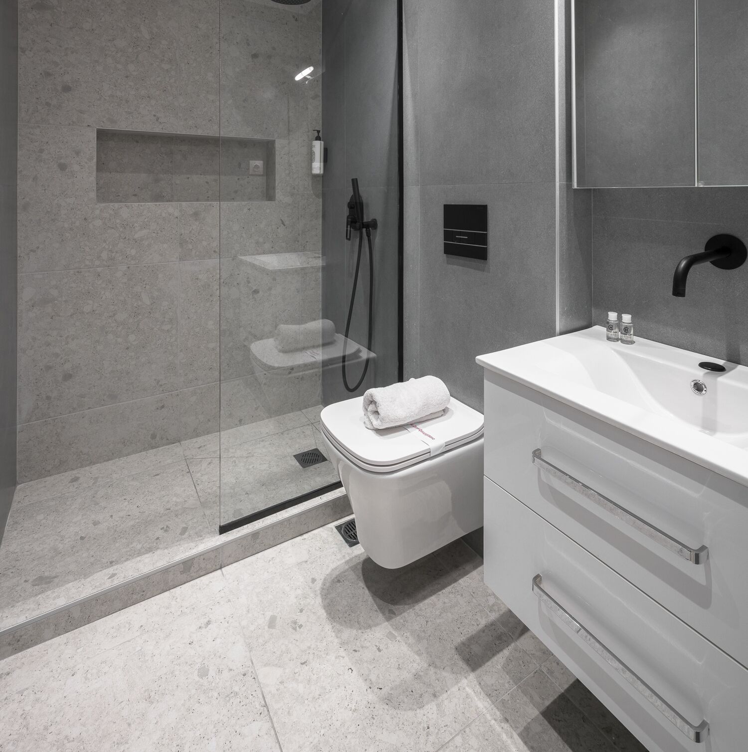 A modern bathroom with a shower, toilet, and vanity.