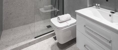 A modern bathroom with a shower, toilet, and vanity.