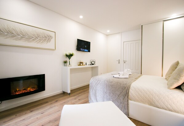 Un dormitorio moderno con chimenea, una cama, un televisor y una mesita de noche.