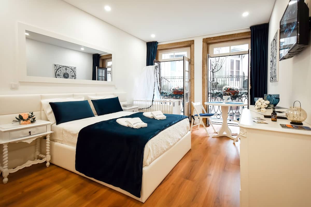Une chambre d’hôtel moderne avec un grand lit, une table de chevet, un bureau et une vue sur le balcon extérieur.