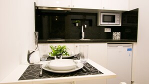 Una cocina moderna con armarios blancos, encimera negra, microondas y lavavajillas.