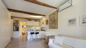 A modern kitchen with white cabinets, a central island with stools, and a dining area with a white table and chairs.
