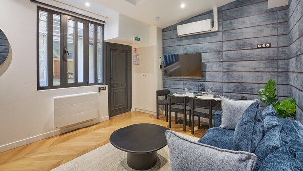 A modern hotel room with a dining area, a black round table, and a blue sofa. - Superb & New Apartment Saint Germain des Pres (Paris)