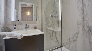 A modern bathroom with a marble sink, a glass-enclosed shower, and a large mirror. - Superb & New Apartment Saint Germain des Pres (Paris)