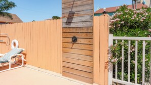 Una valla de madera con un picaporte de metal, una cerca blanca y una silla junto a la piscina.