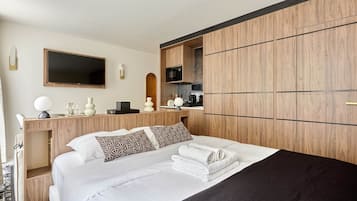 A hotel room with a bed, a desk with a flat-screen TV, a microwave, and a built-in wardrobe.