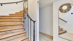 A wooden staircase with a black handrail, white walls, and a mirror reflecting the stairs. - Superb AC Apartment Paris Center Bourse Place (Paris)