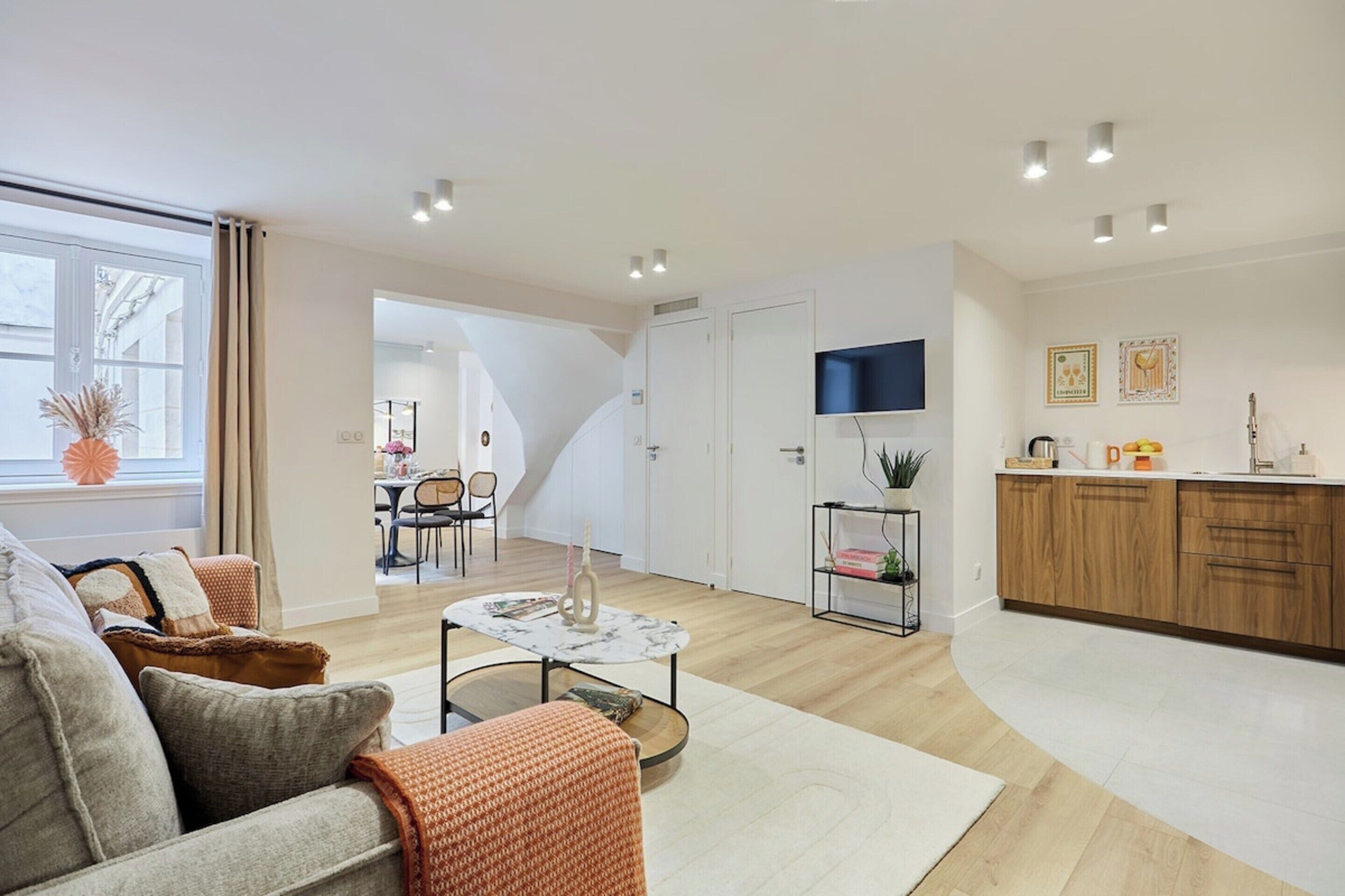 A modern living room with a sofa, coffee table, and a dining area with chairs.