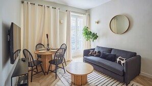A living room with a sofa, coffee table, and dining area with chairs and a table. - Sublim & NEW Apartement St Germain/notre Dame (Paris)