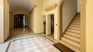 Un pasillo amplio con suelo de cuadros, una escalera y una puerta que da a otra habitación.