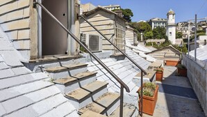 A set of outdoor stone steps leading to a building entrance, with a metal handrail and potted plants at the bottom. - Garibaldi Attic by Wonderful Italy (Genova)