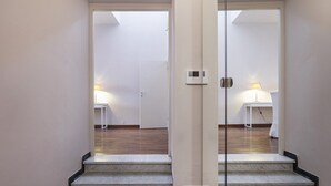 A hallway with a mirrored wall, a staircase, and a room with a door and a lamp. - Garibaldi Attic by Wonderful Italy (Genova)