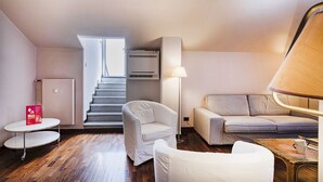 A modern living room with a staircase, a white sofa, a small round table, and a lamp. - Garibaldi Attic by Wonderful Italy (Genova)
