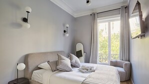 A bedroom with a bed, bedside table, and a window with curtains.