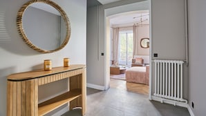 A hallway with a wooden console table, a large mirror, and a white radiator.