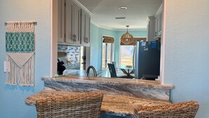 A kitchen with a marble countertop, wicker chairs, and a view to the dining area. - NanDUCKet on the bay in DUCK, NC! (Kitty Hawk)