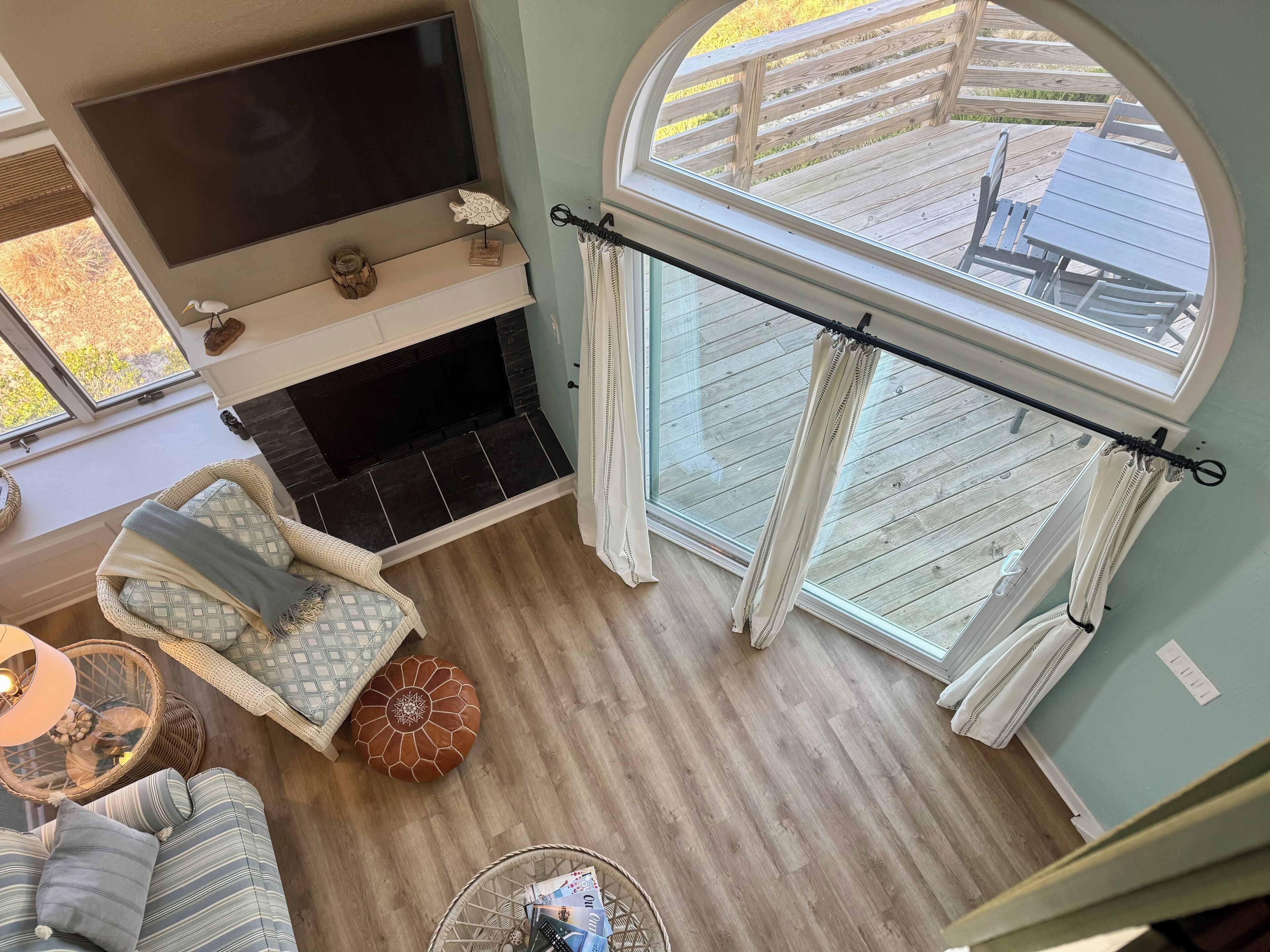 Ein gemütliches Wohnzimmer mit Kamin, einer bequemen Sitzecke und einem großen Fenster mit Blick auf eine Holzterrasse.