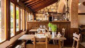 Ein rustikales Restaurant mit Holztischen und -stühlen, einer Ziegelwand und einer Bar mit Flaschen und Gläsern.