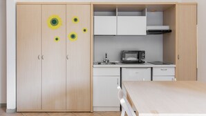 Pieni, käytännöllinen keittiö, jossa on mikroaaltouuni, pesuallas ja valkoiset kaapit.