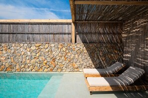 A pool area with stone walls and wooden lounge chairs. - Aristi Villa Ena in Volvi (Aristotelis)