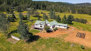 A large house with a green roof, surrounded by a well-maintained lawn and trees. - Romantic Vineyard Getaway in Oakland: Mtn Views! (Oakland)