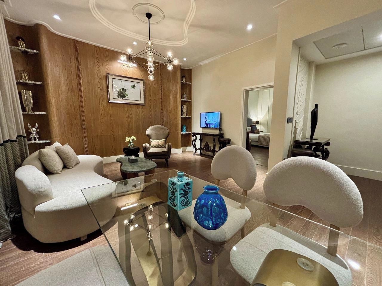 Een moderne woonkamer met een bank, fauteuils, een salontafel en decoratieve objecten.