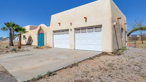 A single-story building with a garage, a blue door, and a small garden with a palm tree. - Desert Retreat in Golden Valley: Courtyard & Views (Golden Valley)