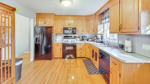 A modern kitchen with wooden cabinets, stainless steel appliances, and a white countertop. - Pool, Deck & Grill: Spacious Apt in Naugatuck! (Naugatuck)