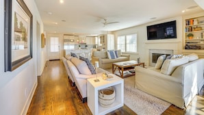 A spacious living area with a sofa, coffee table, and a fireplace. There is a kitchen in the background with cabinets and a television mounted above the fireplace. - 1 Mi to Dtwn Fayetteville: Home w/ Fenced Yard (Fayetteville)