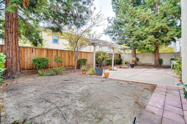 A backyard with a wooden fence, potted plants, a pergola, and a concrete patio. - Centrally Located Home w/ Yard in Hayward! (Hayward)