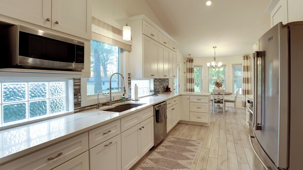 A modern kitchen with white cabinetry, stainless steel appliances, and a large window overlooking a snowy landscape. - Holland Home: Walk to the Beach! (Holland)