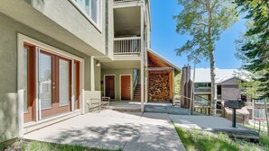 A modern building with a covered porch, a staircase, and a firewood storage area. - Hike, Bike & Fish: Brian Head Resort Condo! (Brian Head)