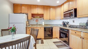 A kitchen with wooden cabinets, a refrigerator, a microwave, and a dishwasher. - Hike, Bike & Fish: Brian Head Resort Condo! (Brian Head)