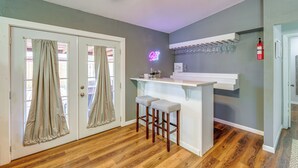 Une salle avec un coin bar, un plancher en bois et un panneau lumineux au néon.
