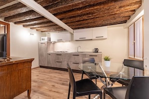Una cucina moderna con travi in legno, un tavolo da pranzo in vetro e sedie nere.