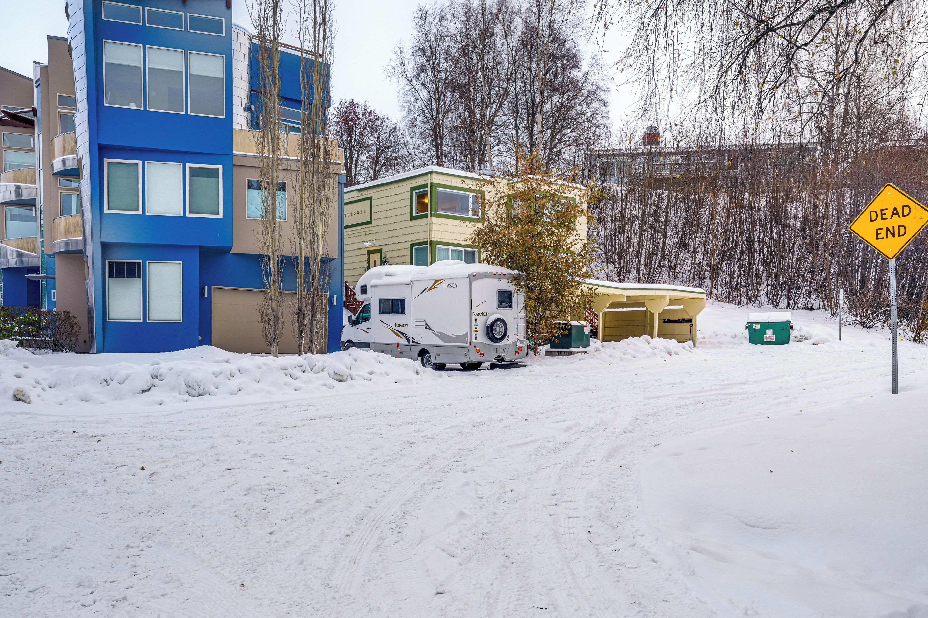 A snow-covered road with a camper parked on the side.