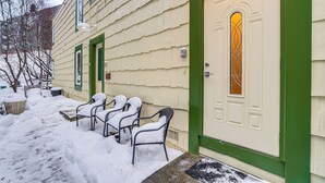 A building with a green door and a window with a decorative design. There are four chairs with snow on them, and a pathway covered in snow. - 1 Mi to Dtwn: Cozy Condo in Anchorage! (Anchorage)