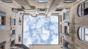 A high-rise building with multiple balconies, large windows, and a clear sky view.
