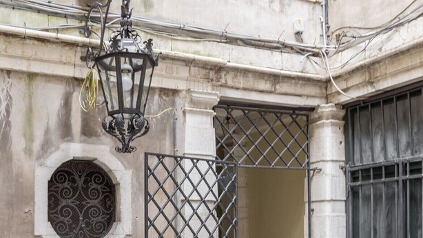 A building with a metal gate, a small table, and a decorative lantern.