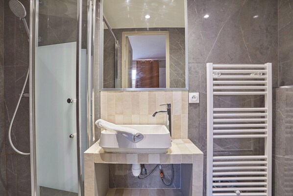 A modern bathroom with a glass-enclosed shower, a sink with a towel, and a white towel rack. - Superb Apartment 2 Bedrooms Center of Paris (Paris)